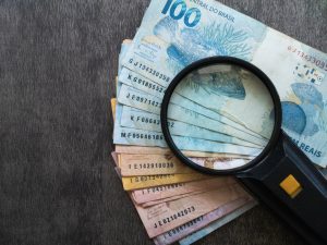notas de reais e lupa