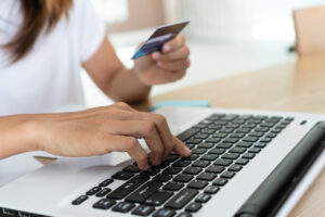Mulher utilizando computador e cartão de crédito